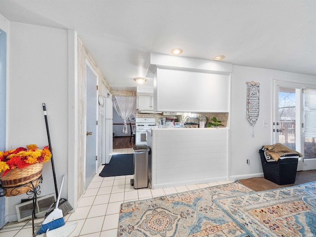 kitchen featuring light tile patterned floors, white cabinets, white range, and tasteful backsplash