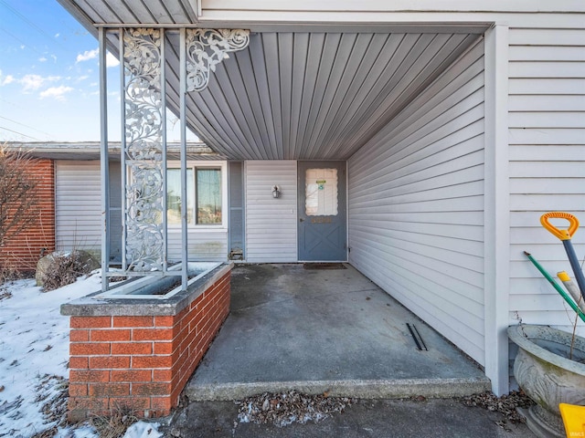 snow covered property entrance with a patio area