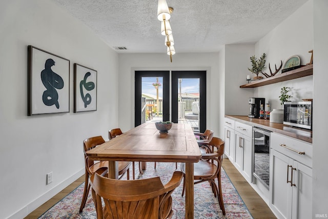 dining room with a textured ceiling, wine cooler, and dark hardwood / wood-style flooring