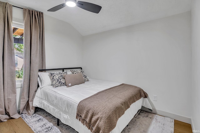 bedroom featuring ceiling fan, hardwood / wood-style flooring, and lofted ceiling