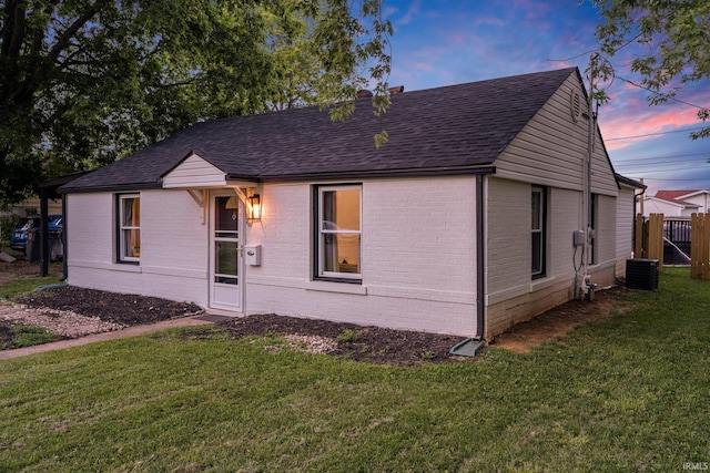 view of front of house featuring cooling unit and a lawn