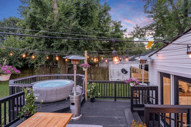 deck at dusk featuring an outdoor fire pit and a lawn