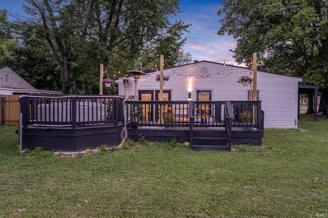 back house at dusk featuring a deck and a yard