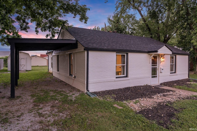 view of front of house with a yard, a storage shed, and a carport