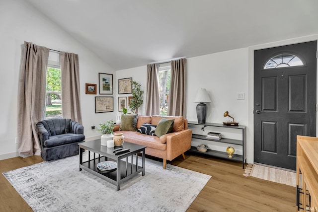 living room featuring lofted ceiling, light hardwood / wood-style flooring, and a wealth of natural light