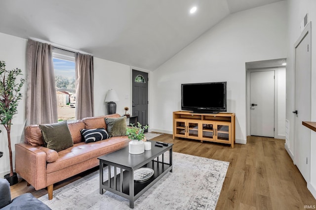 living room with high vaulted ceiling and light hardwood / wood-style flooring