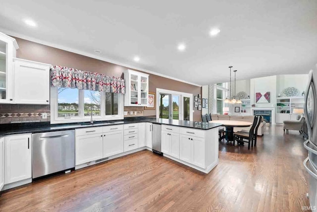 kitchen with kitchen peninsula, dishwasher, hanging light fixtures, sink, and hardwood / wood-style flooring