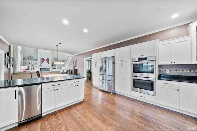 kitchen featuring light hardwood / wood-style floors, white cabinetry, decorative backsplash, pendant lighting, and stainless steel appliances