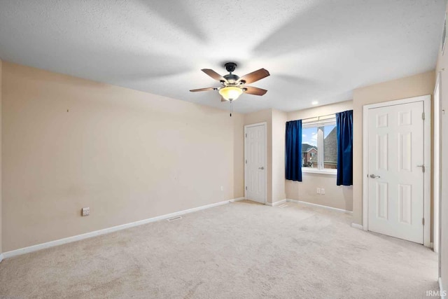 unfurnished bedroom featuring ceiling fan, a textured ceiling, and light carpet