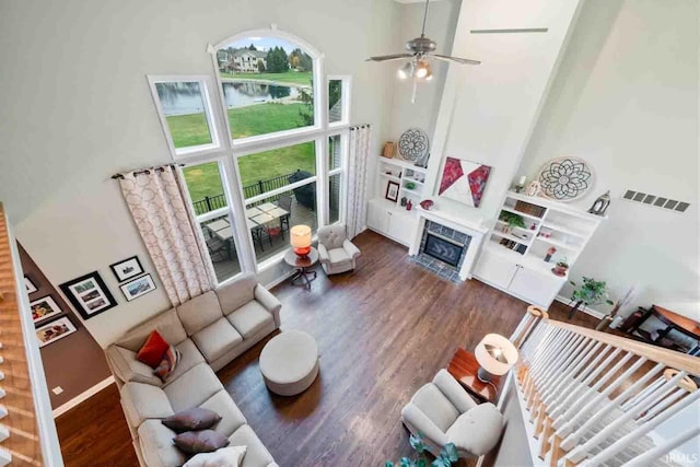 living room with a high ceiling, ceiling fan, a high end fireplace, and dark hardwood / wood-style floors