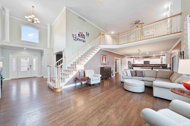 living room featuring hardwood / wood-style flooring, ornamental molding, a towering ceiling, and ceiling fan with notable chandelier