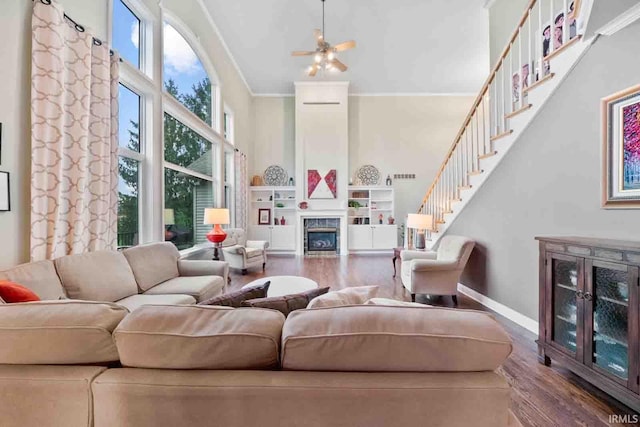 living room with hardwood / wood-style flooring, crown molding, and a towering ceiling