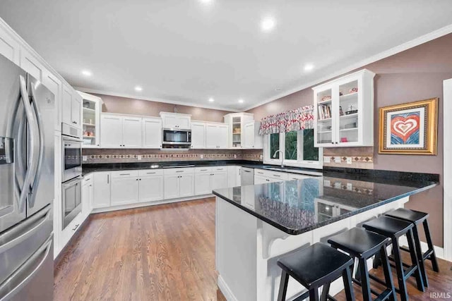 kitchen featuring a kitchen breakfast bar, white cabinetry, appliances with stainless steel finishes, and dark stone countertops