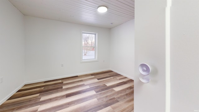 empty room featuring light wood-type flooring and wood ceiling