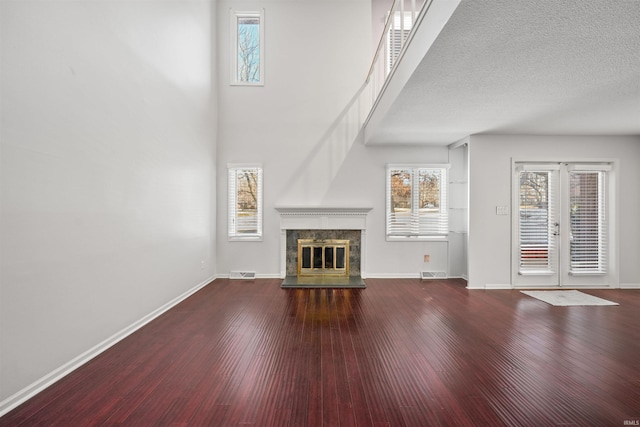 unfurnished living room with a textured ceiling, wood-type flooring, french doors, a fireplace, and built in features