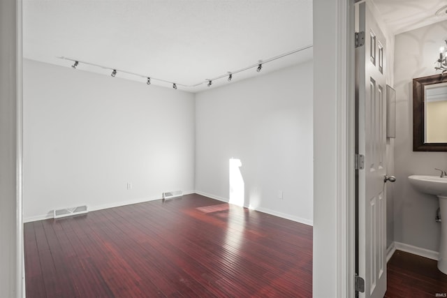 unfurnished room featuring rail lighting and dark wood-type flooring