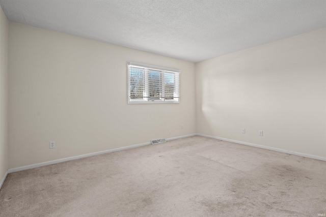 carpeted empty room featuring a textured ceiling