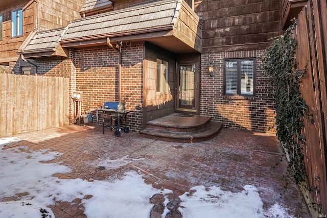 snow covered property entrance with a patio area