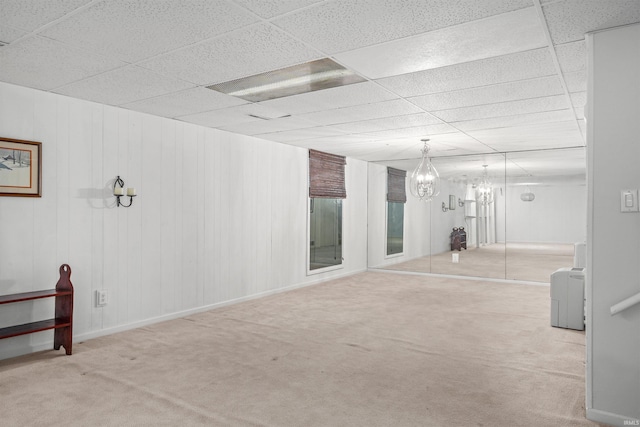 empty room with a drop ceiling, a notable chandelier, and carpet