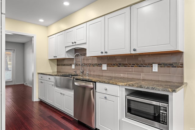 kitchen with white cabinetry, appliances with stainless steel finishes, and dark stone counters