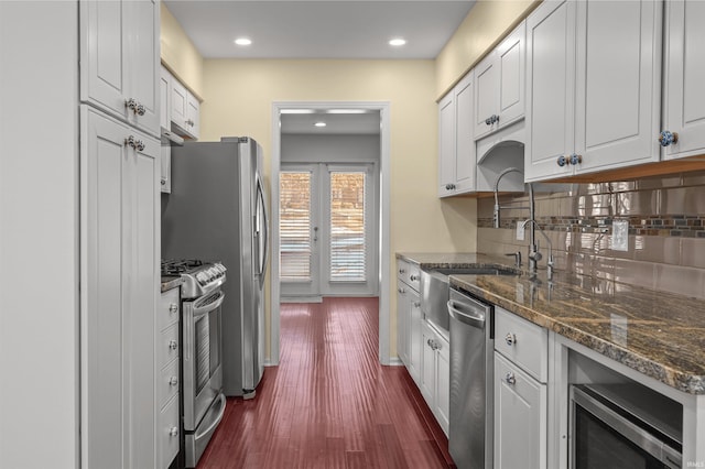 kitchen with white cabinets, stainless steel appliances, dark stone countertops, and tasteful backsplash