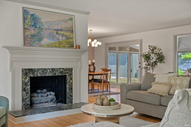 living room featuring light wood-type flooring, a chandelier, and a premium fireplace