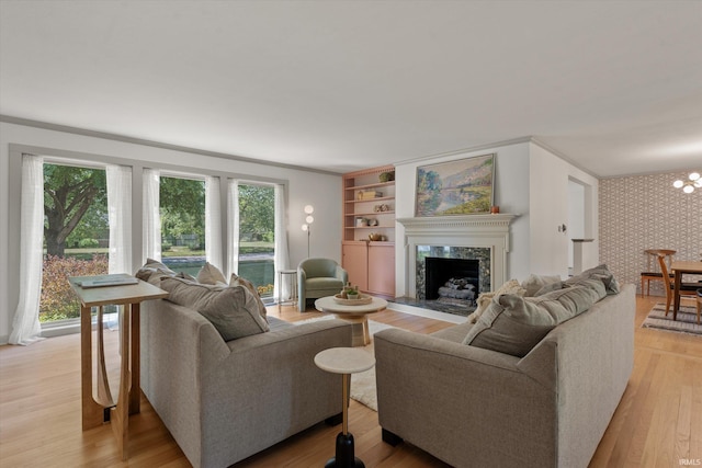 living room featuring light hardwood / wood-style flooring, a notable chandelier, a high end fireplace, and ornamental molding