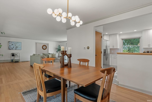 dining area with sink, light hardwood / wood-style floors, and crown molding