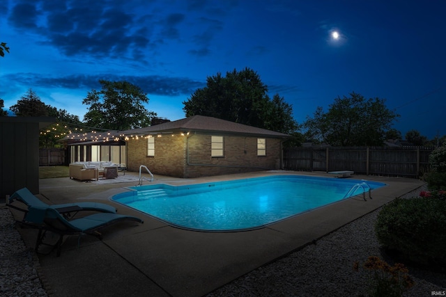 pool at dusk featuring a diving board and a patio