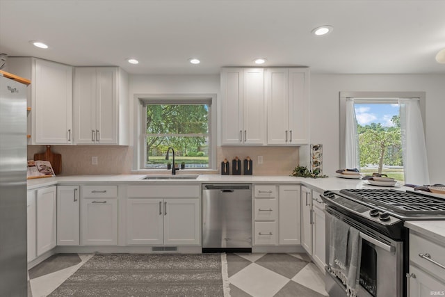 kitchen with sink, backsplash, white cabinets, and appliances with stainless steel finishes