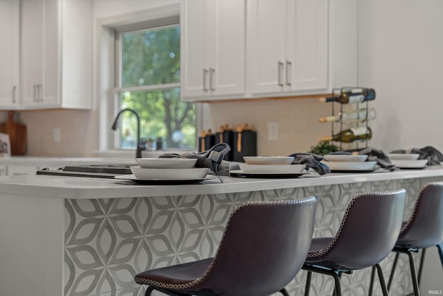 kitchen featuring a kitchen bar and white cabinetry