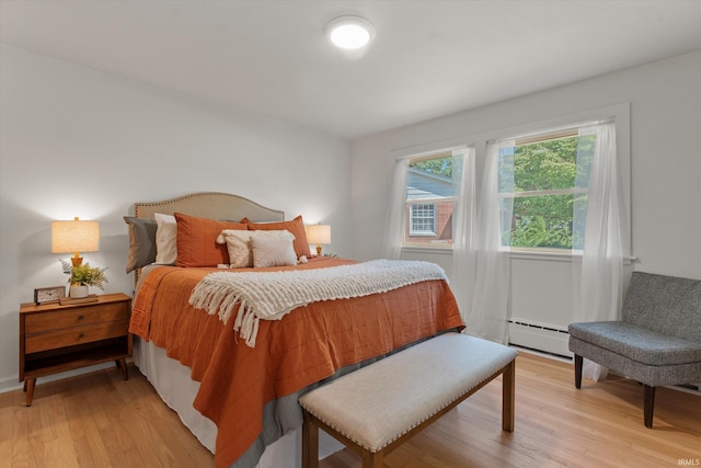 bedroom featuring a baseboard heating unit and light hardwood / wood-style flooring