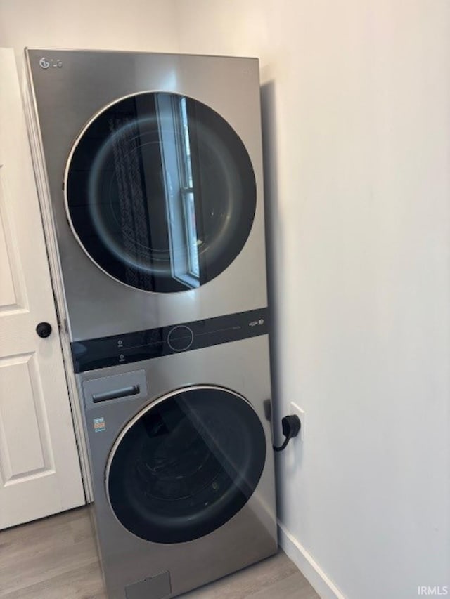 laundry room with light hardwood / wood-style flooring and stacked washing maching and dryer