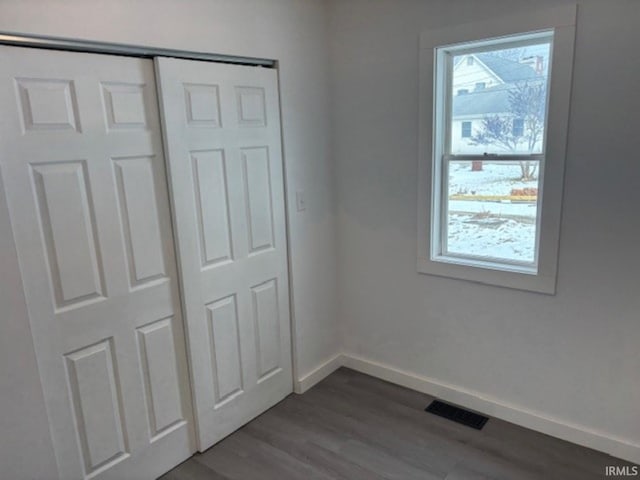 unfurnished bedroom with hardwood / wood-style flooring, multiple windows, and a closet