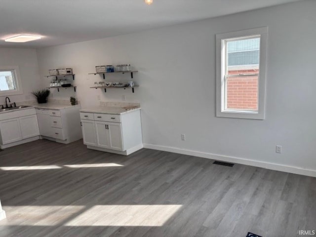 bar with sink, light wood-type flooring, white cabinetry, and plenty of natural light