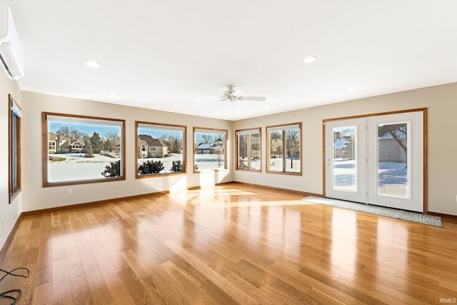 unfurnished living room featuring ceiling fan, an AC wall unit, and light hardwood / wood-style flooring