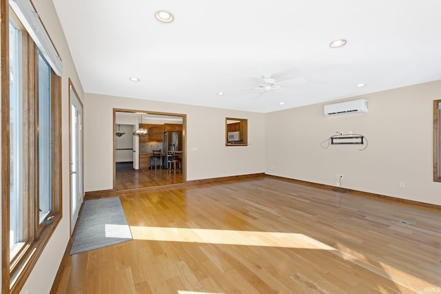 spare room featuring light hardwood / wood-style floors, ceiling fan, and a wall mounted air conditioner