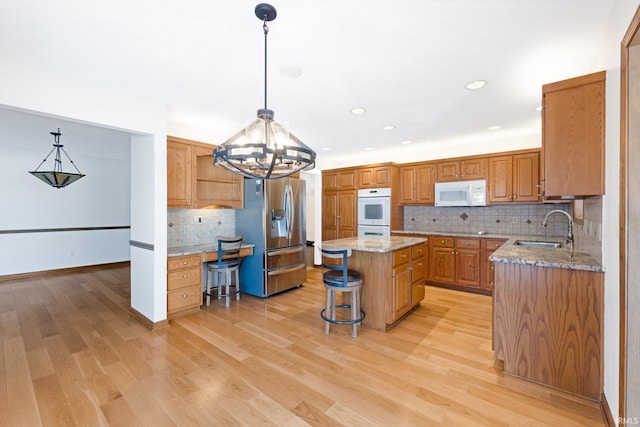 kitchen with pendant lighting, sink, white appliances, and a kitchen island