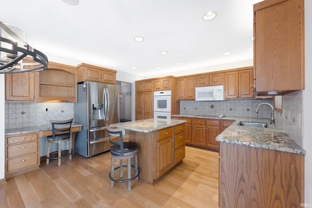 kitchen featuring sink, white appliances, light hardwood / wood-style flooring, and a kitchen island