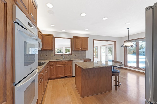 kitchen with pendant lighting, appliances with stainless steel finishes, a center island, sink, and backsplash