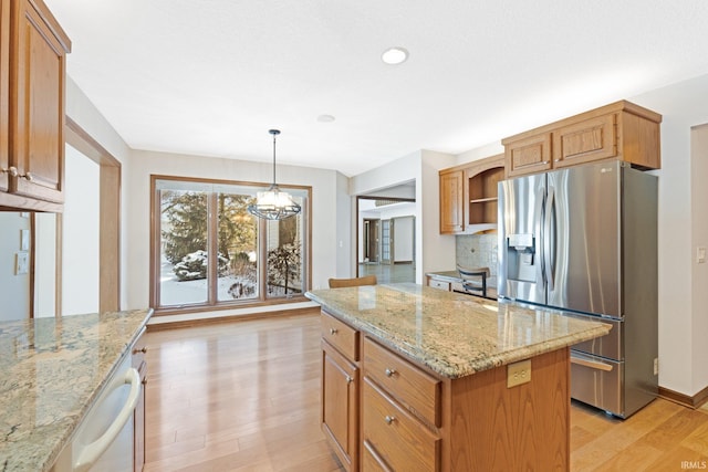 kitchen with a kitchen island, light stone counters, decorative light fixtures, and appliances with stainless steel finishes