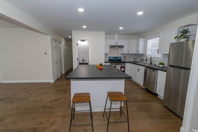 kitchen featuring appliances with stainless steel finishes, white cabinets, a kitchen island, sink, and a breakfast bar area