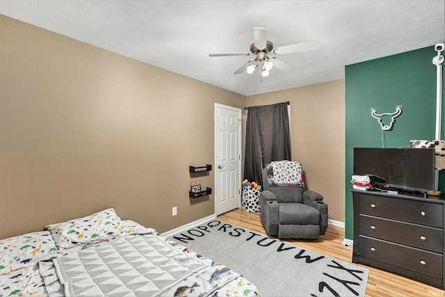 bedroom with ceiling fan, hardwood / wood-style floors, and a textured ceiling