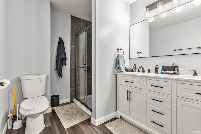 bathroom with hardwood / wood-style flooring, an enclosed shower, vanity, and toilet