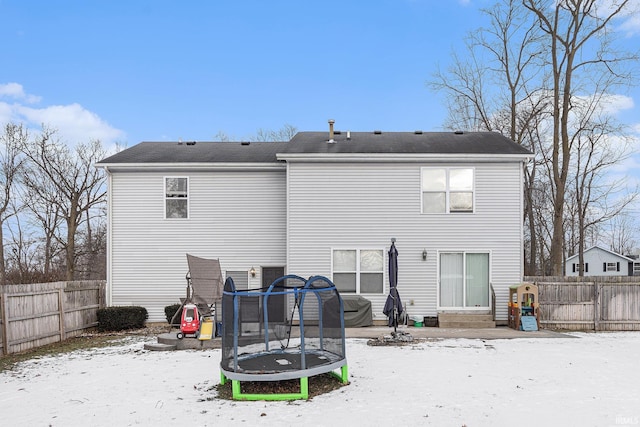 snow covered rear of property featuring a trampoline