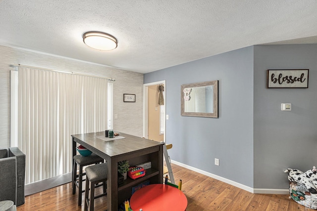 dining space with hardwood / wood-style flooring and a textured ceiling