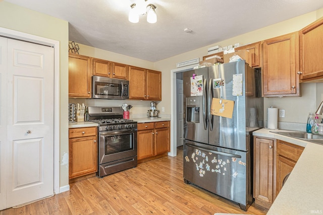 kitchen featuring sink, a textured ceiling, stainless steel appliances, and light wood-type flooring