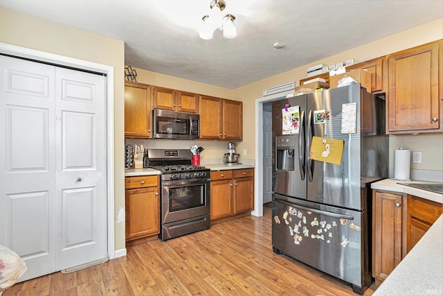 kitchen featuring stainless steel appliances, light hardwood / wood-style flooring, and a textured ceiling