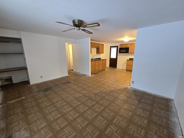 unfurnished living room with sink, ceiling fan, and dark parquet flooring