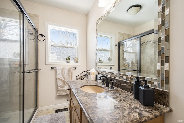 bathroom with vanity, a shower with door, and tasteful backsplash